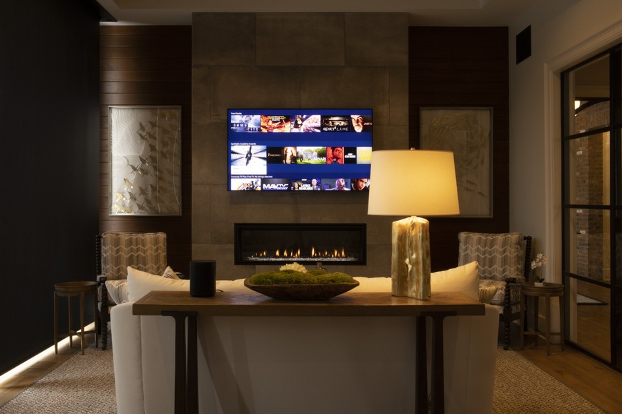 A living room with a TV above a fireplace and warm smart lighting. 