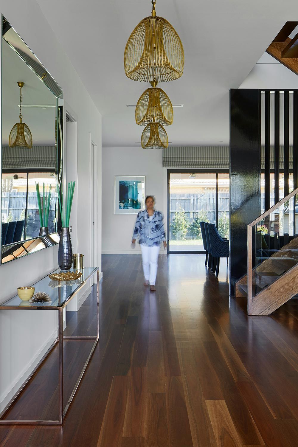 Blurry woman walking on the hallway of a modern house with nougat wood floors